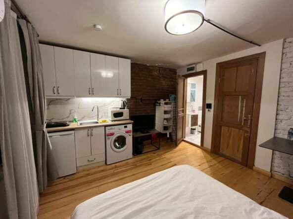 A room with a bed and a washing machine Description automatically generated